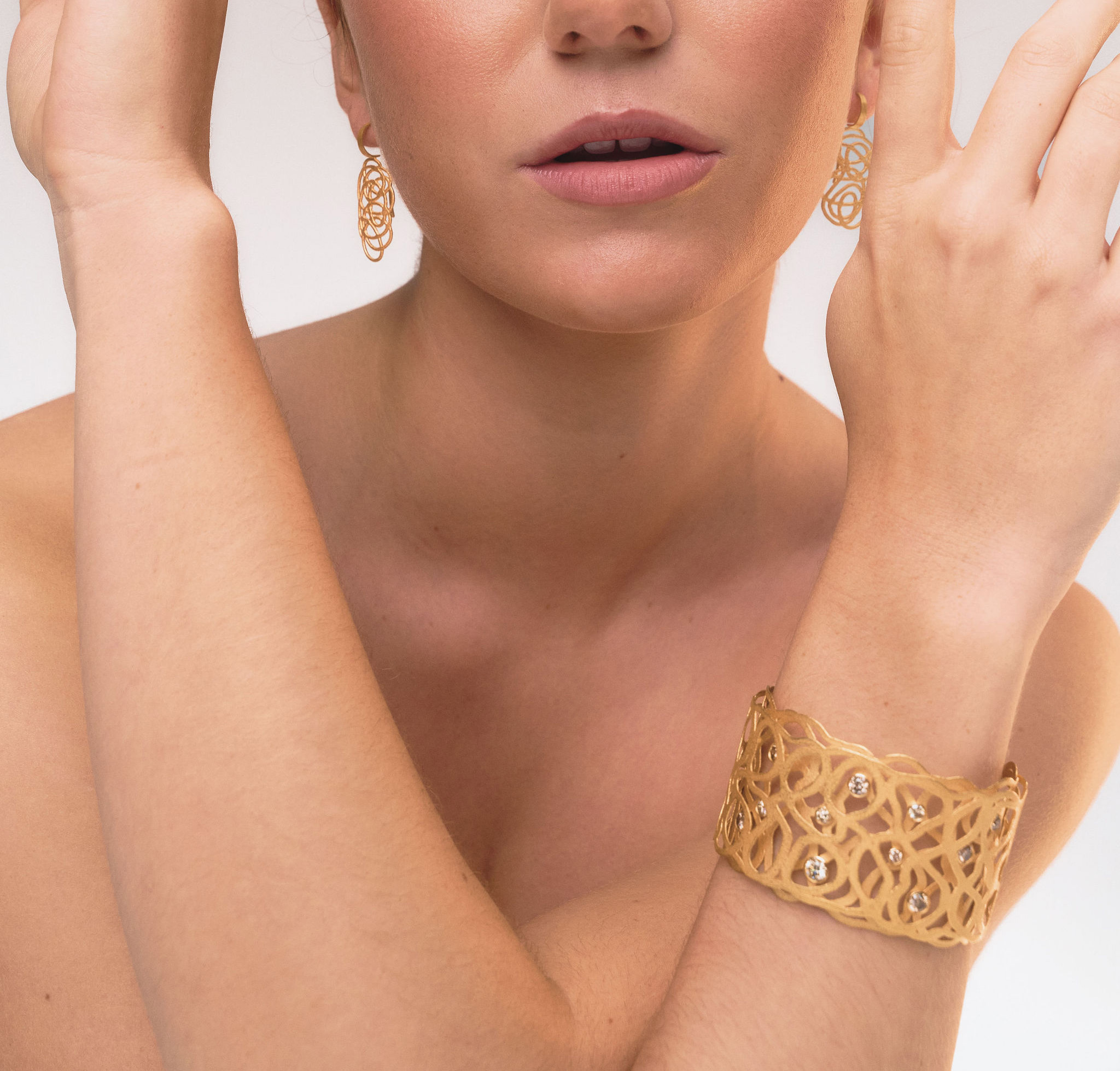 Model mit handgefertigten Ohrringen und Armreif aus 18 Karat Gold